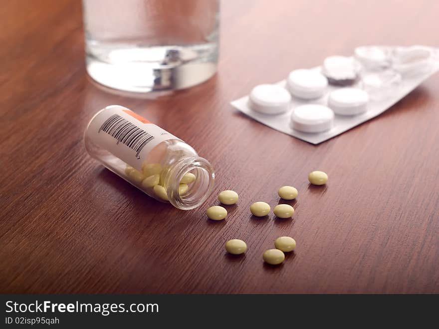 Pills and glass of water on table. Pills and glass of water on table