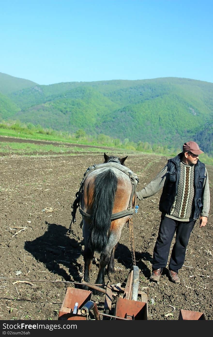 Men holding his horse and plowing the land at the beginning of the spring. Men holding his horse and plowing the land at the beginning of the spring