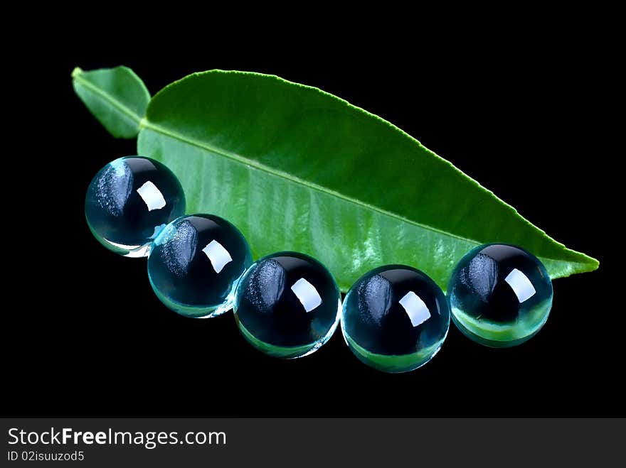 Close-up of green leaf and glass balls on a black background