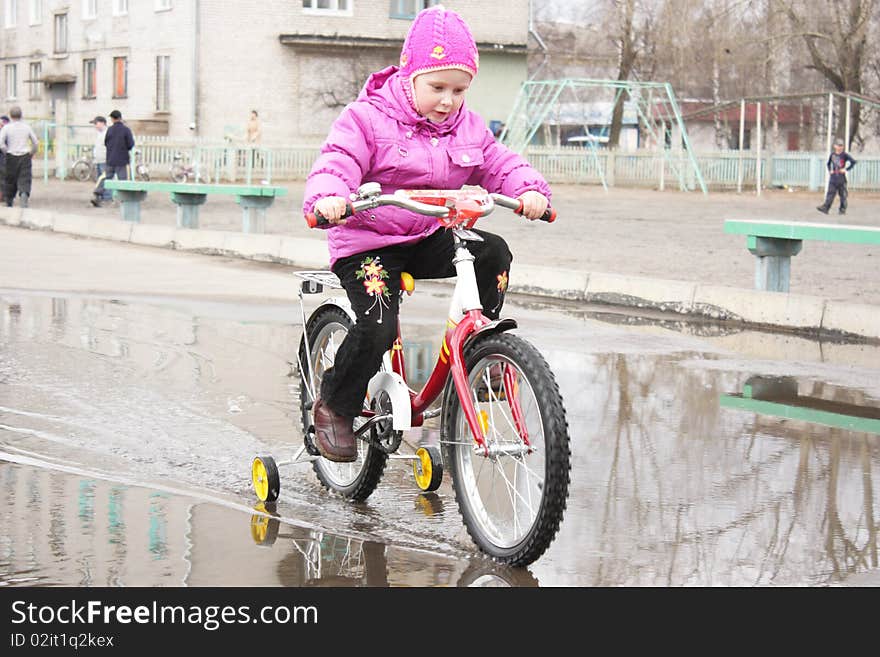 A girl goes through a puddle on a bicycle. A girl goes through a puddle on a bicycle.