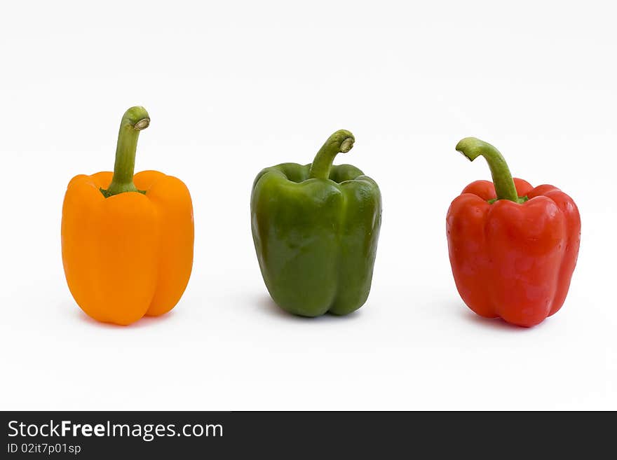 Red yellow and green peppers on white