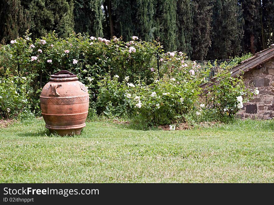 Big brown vase on green grass near flowers. Big brown vase on green grass near flowers