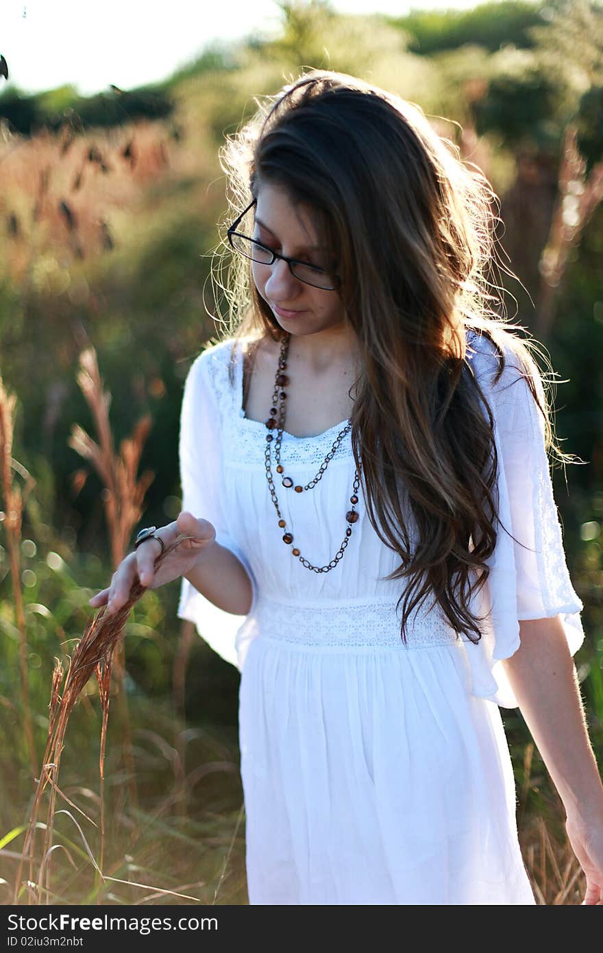 Long haired teenager wearing glasses walking standing in a field. Long haired teenager wearing glasses walking standing in a field.