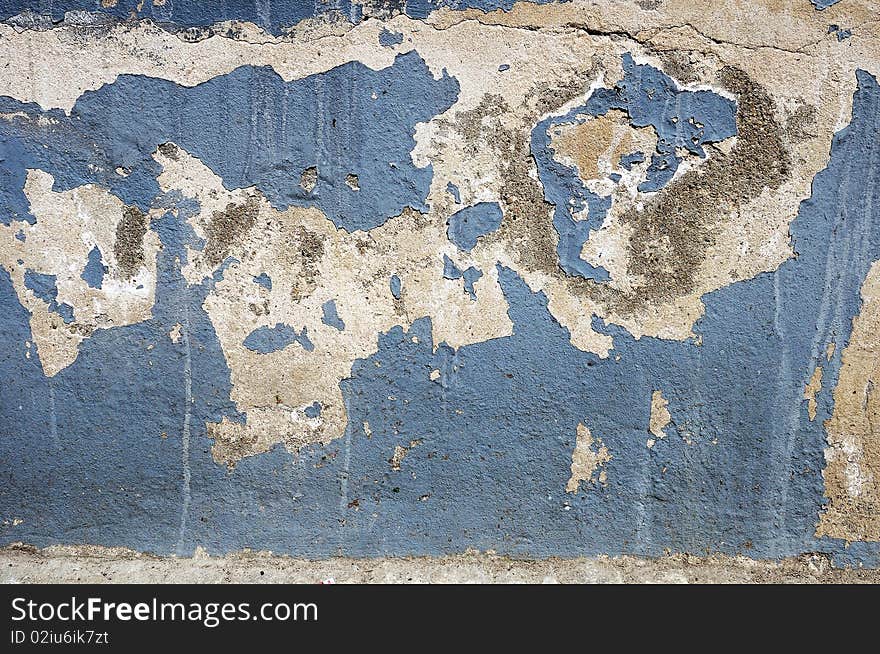 Fragment of tumbledown light blue painted stone wall. Fragment of tumbledown light blue painted stone wall