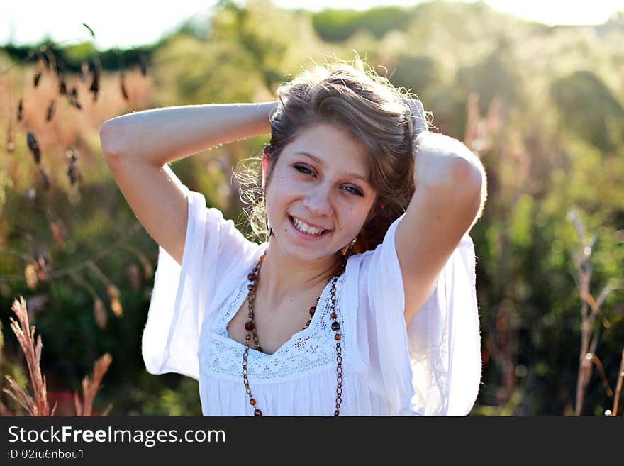 Casual portrait of a beautiful smiling girl with her arms above her head outdoors in spring or summer time. Casual portrait of a beautiful smiling girl with her arms above her head outdoors in spring or summer time.