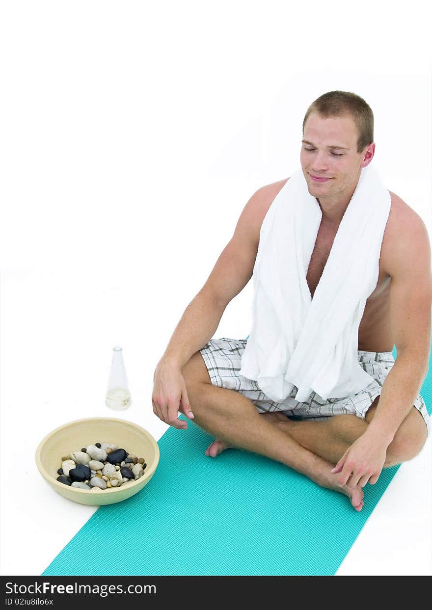 Handsome man relaxing and sitting on a green mat meditating. Handsome man relaxing and sitting on a green mat meditating