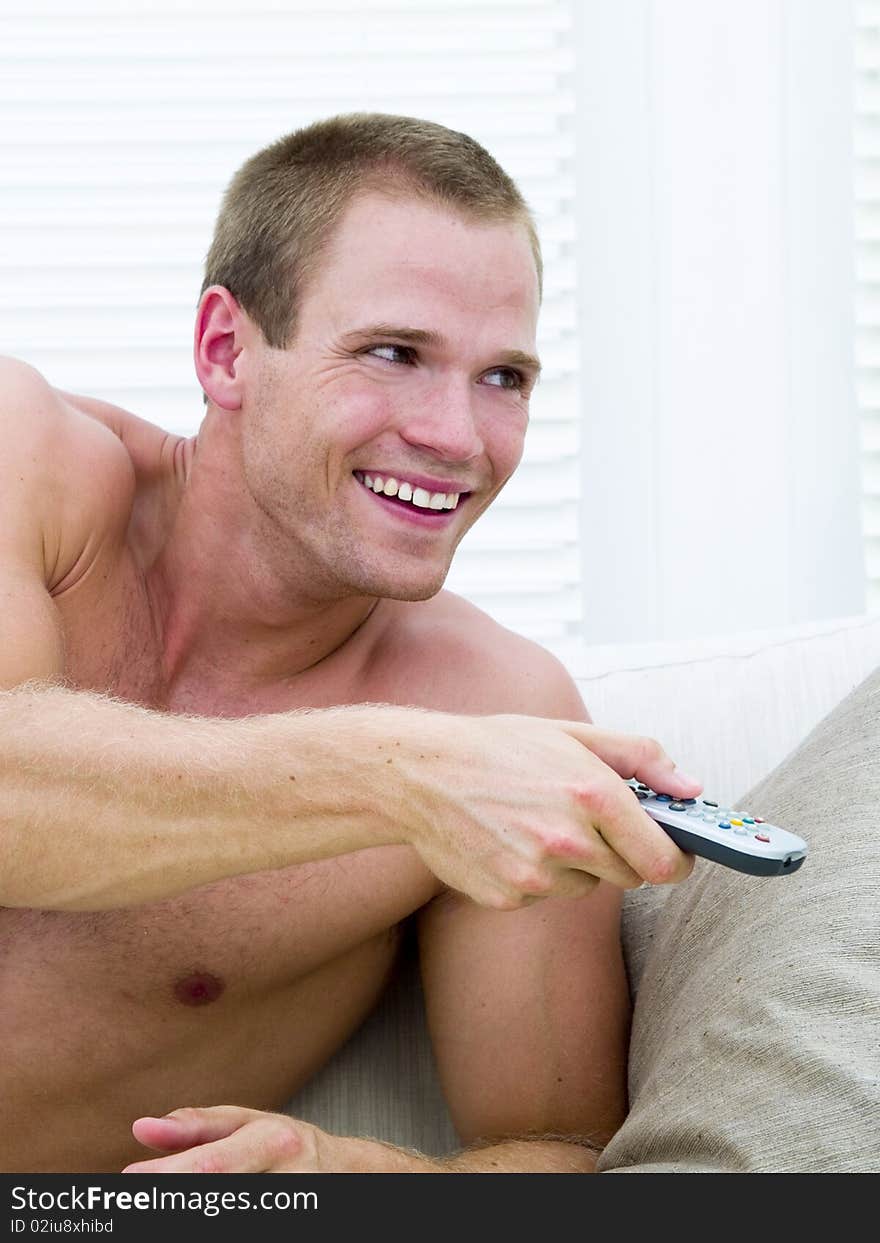 Muscular man lying on the sofa watching a funny movie. Muscular man lying on the sofa watching a funny movie