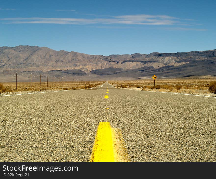 Desert road with mountains and powerlines through Death Valley National Park, California. Desert road with mountains and powerlines through Death Valley National Park, California