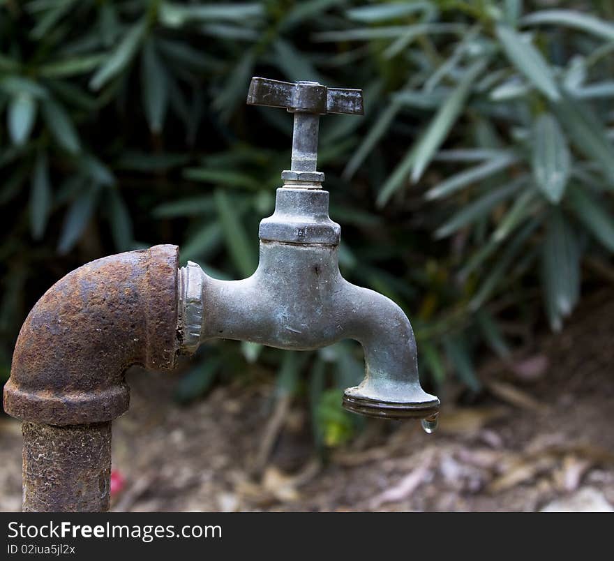 Old rusty water tap with one water drop