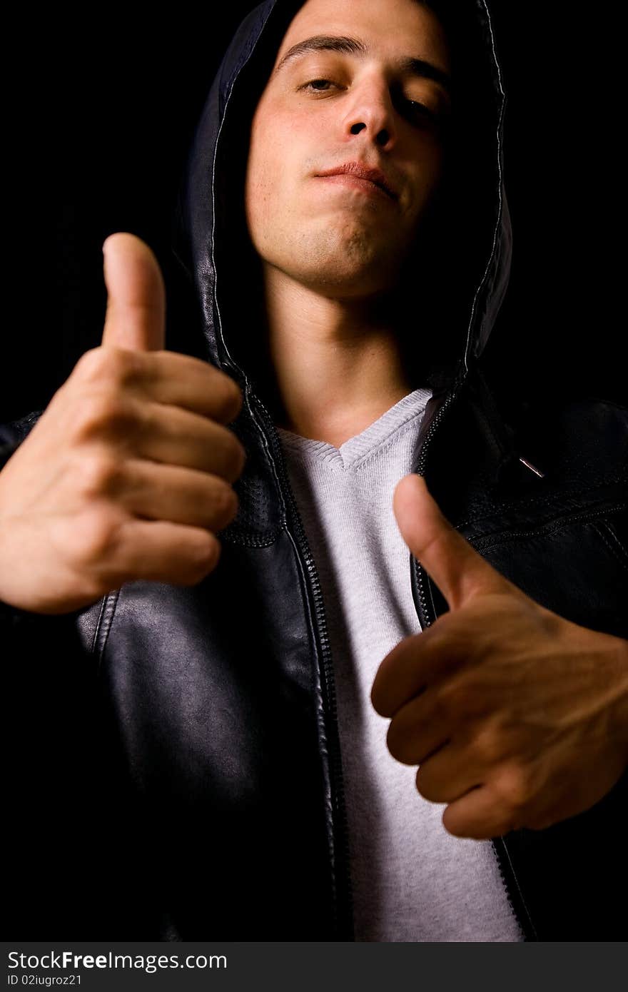 Young casual man tumbs up against dark background