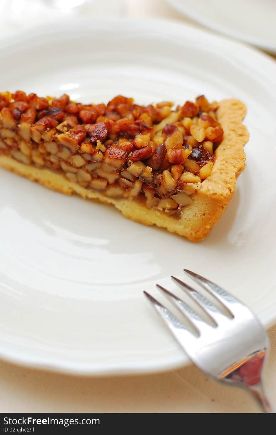 Hazel nut tart with fork on white plate. For concepts such as food and beverage, diet and nutrition, and healthy eating.