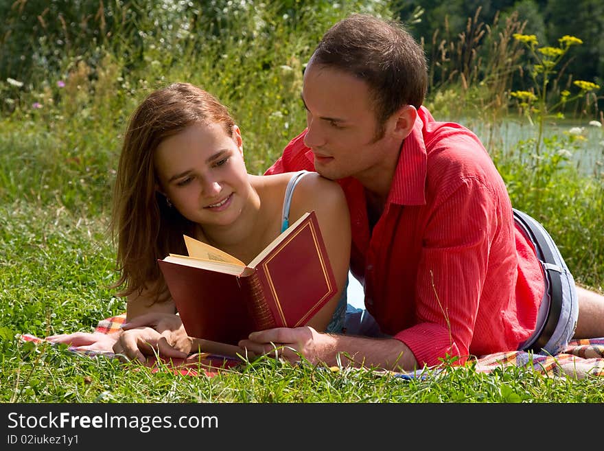 Smiling couple reading and relaxing at the park.