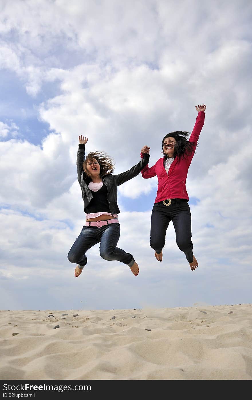 An image showing young girls jumping on the beach. An image showing young girls jumping on the beach