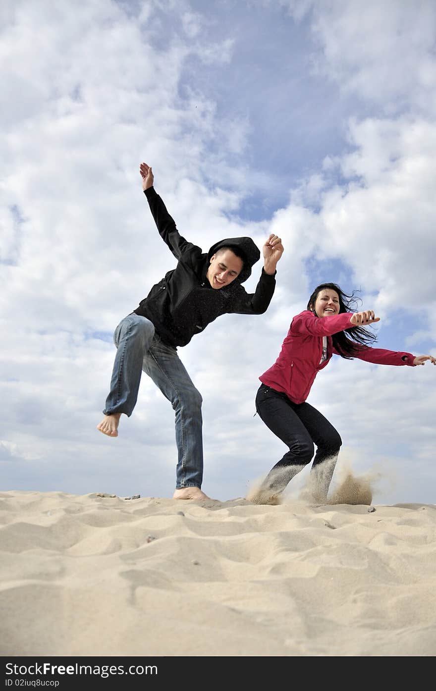 An image showing young girl and boy jumping on the beach. An image showing young girl and boy jumping on the beach