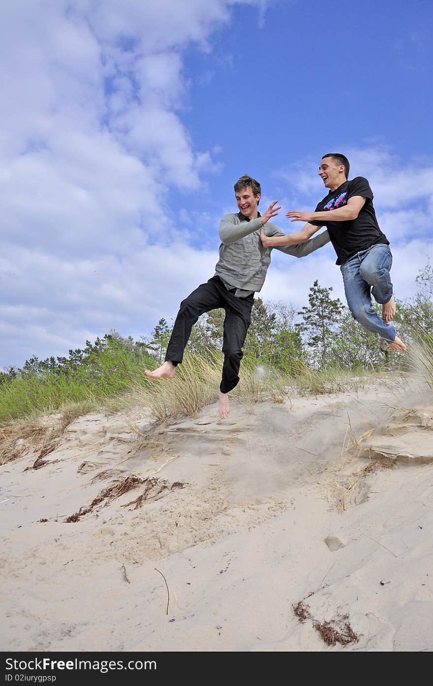 An image showing young boys jumping on the beach. An image showing young boys jumping on the beach