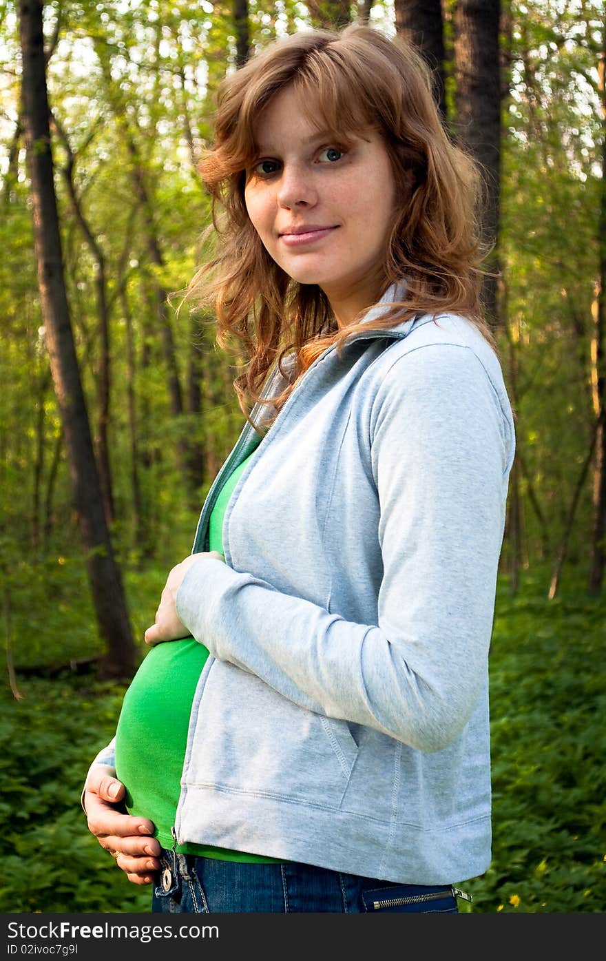 Young pregnant woman holding her hands on her tummy