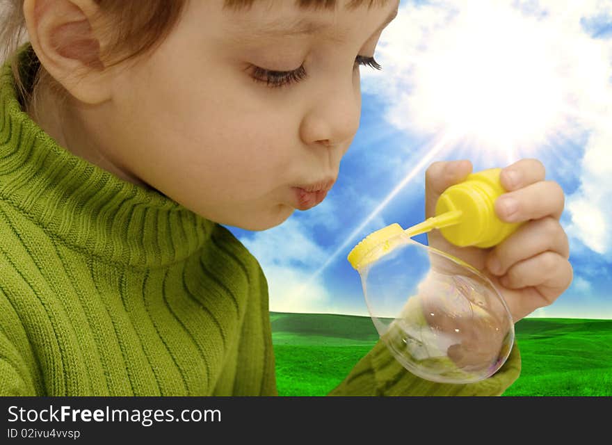 The girl inflating soap bubbles on a meadow