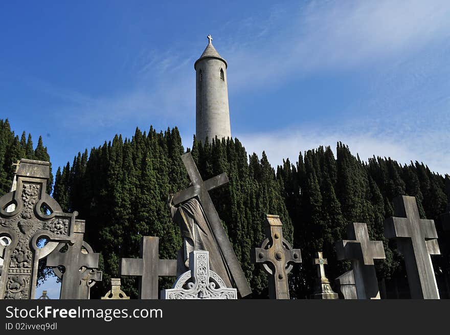 Image of a graveyard in dublin ireland with celtic cross headstones and cemetery tower in background