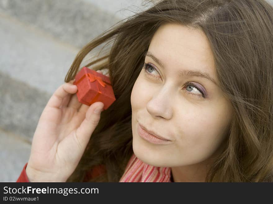 Young woman sitting on the stairs to the street, and holds a red gift box. Young woman sitting on the stairs to the street, and holds a red gift box