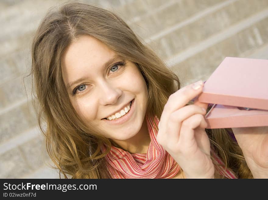 Young woman sitting on the stairs to the street, and holds a pink gift box. Young woman sitting on the stairs to the street, and holds a pink gift box