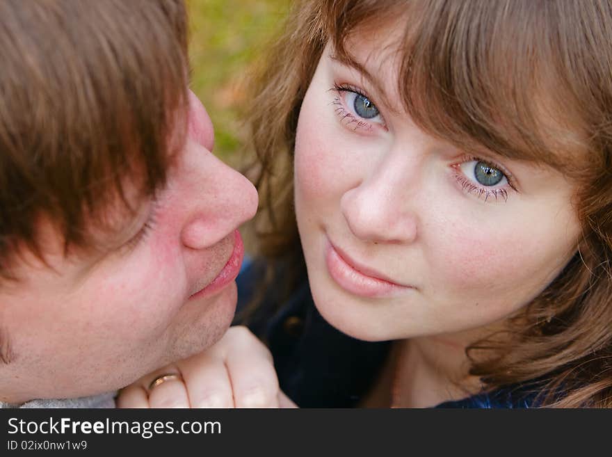 Close-up portrait of a young beautiful wife and her husband, he is looking at her. Close-up portrait of a young beautiful wife and her husband, he is looking at her