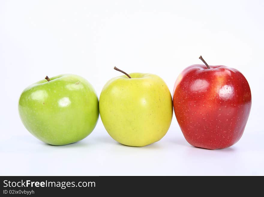 Three apples (green, yellow,red) in a raw on white background