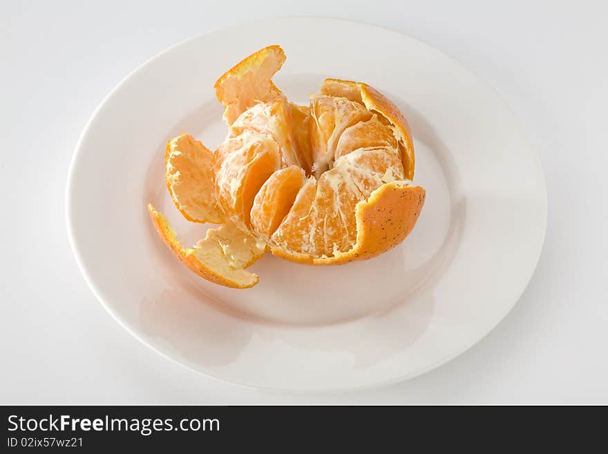 Mandarin orange partially peeled on white plate