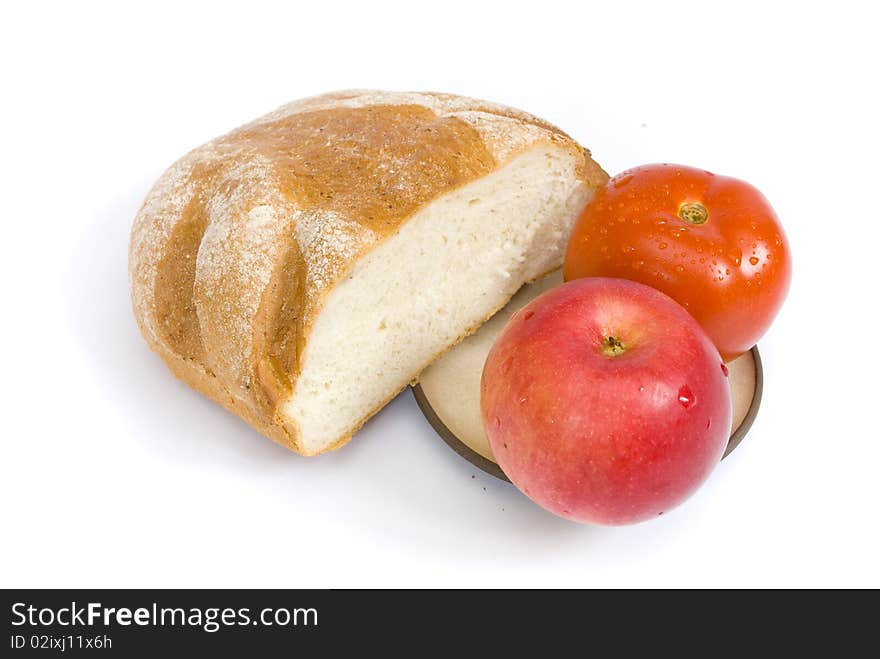 White bread, dusted with flour, red tomato and ripe apple covered with drops of water, on a plate, on a white background. White bread, dusted with flour, red tomato and ripe apple covered with drops of water, on a plate, on a white background