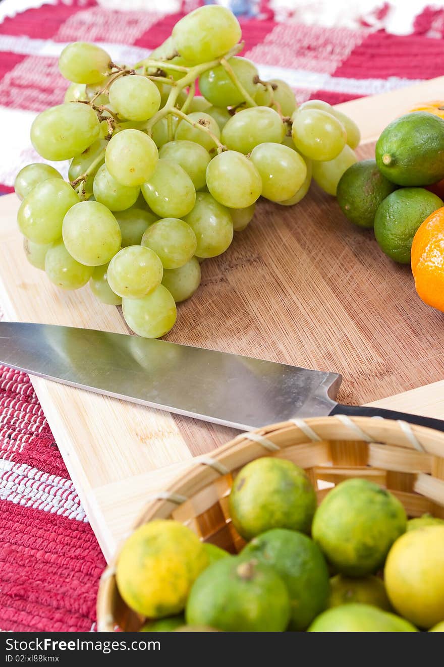 Fresh grapes on a cutting board alongside some other fruits. Fresh grapes on a cutting board alongside some other fruits