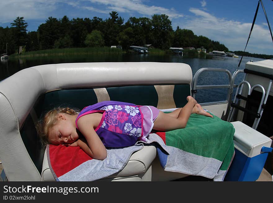 A young girl rests in the sunshine on a boat as it goes for a spin around a lake. A young girl rests in the sunshine on a boat as it goes for a spin around a lake.