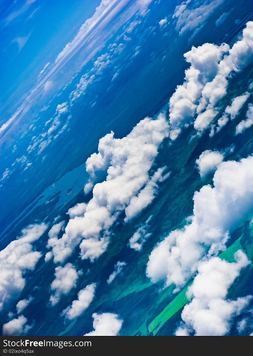 Aerial view of clouds over lake, fields and hills in turquoise blue tone