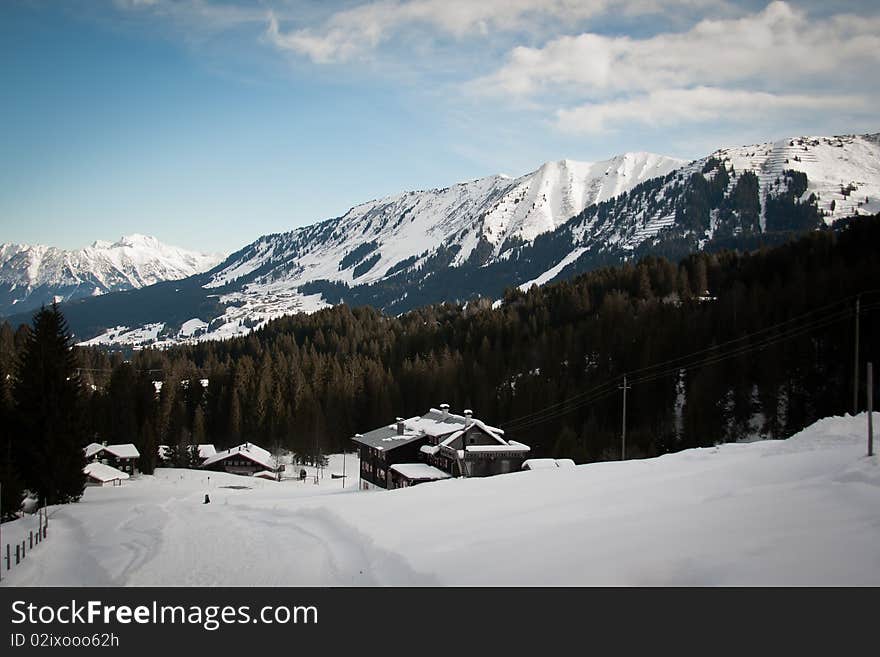 A hut in a snow landscape in austria. A dog sits on the snow. A hut in a snow landscape in austria. A dog sits on the snow.