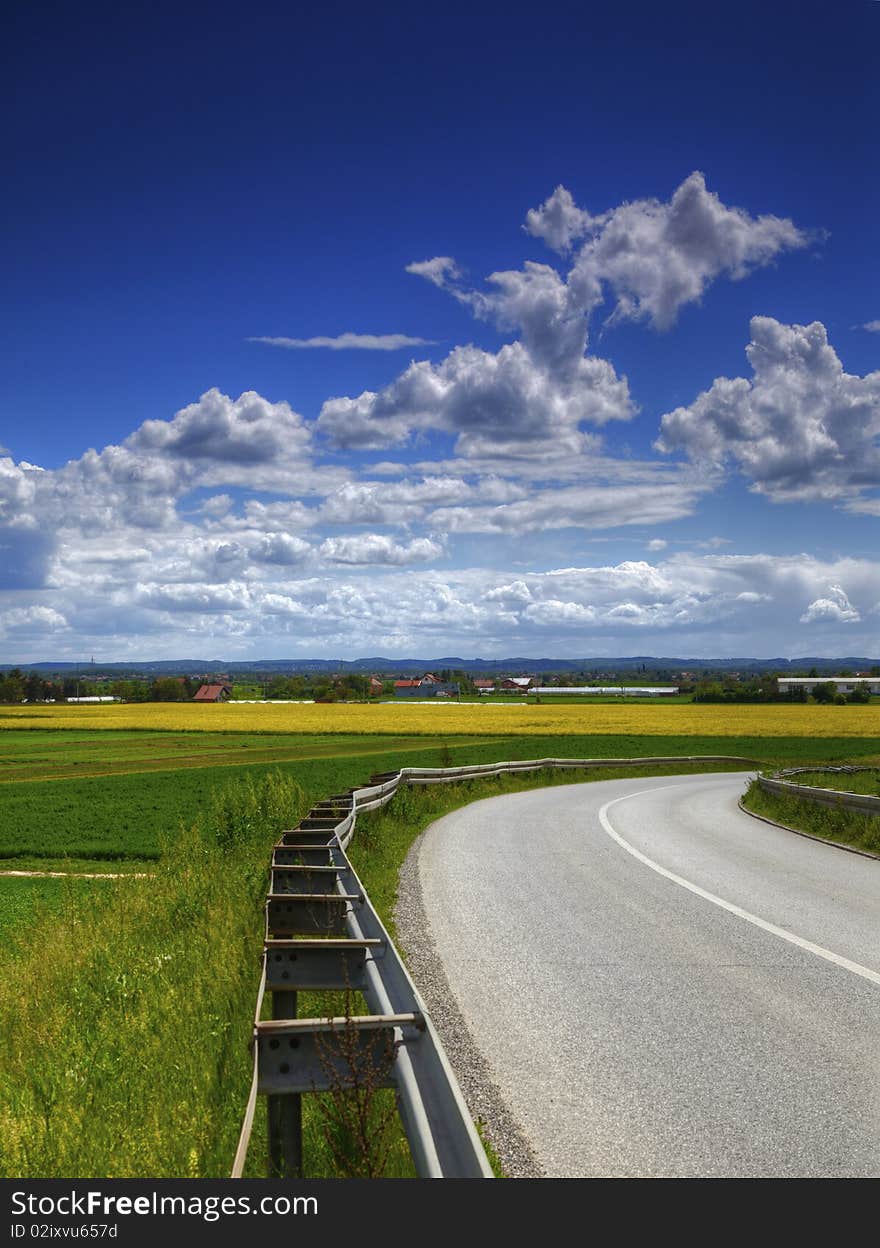 Agriculture landscape road and blue cloudy sky