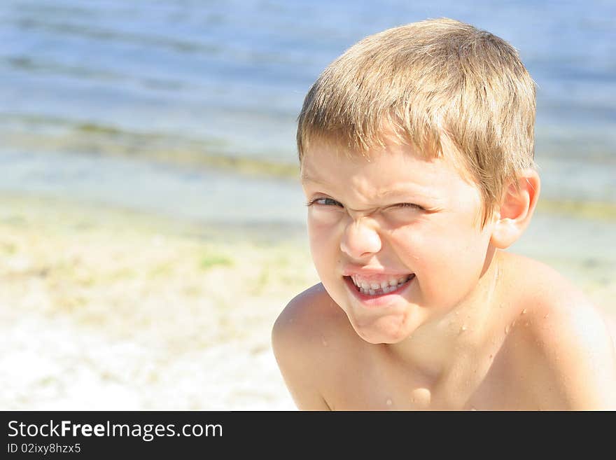 Cute little boy winking at the beach