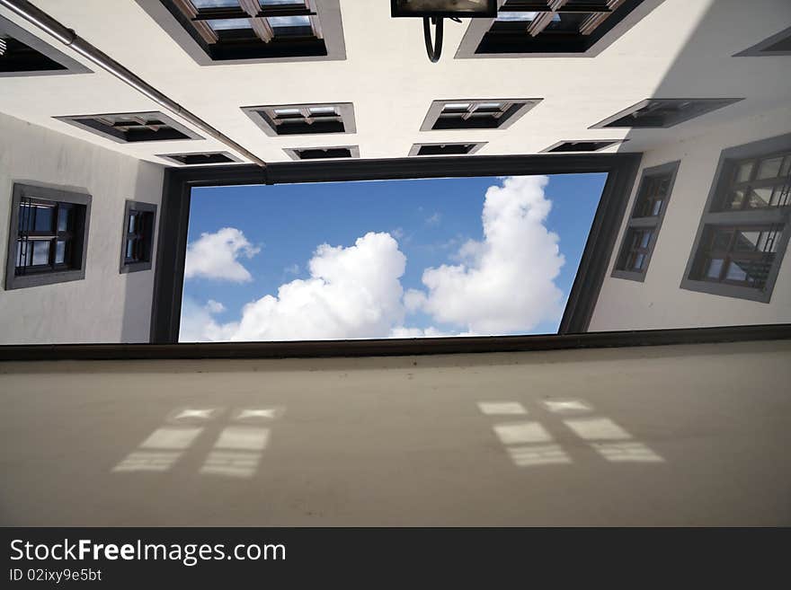 Building view from below with wall and windows and cloudy sky in the middle