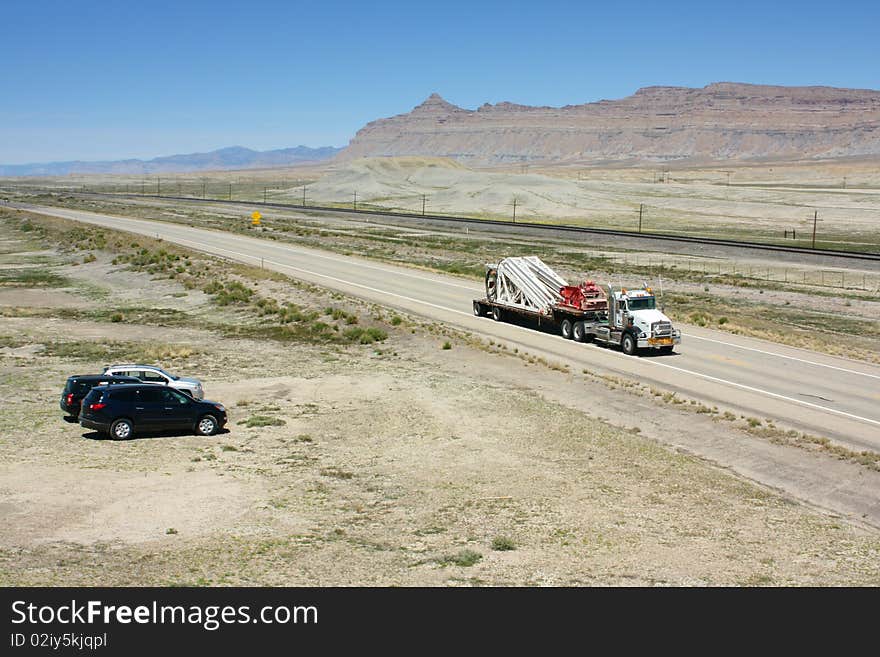 An American style truck carrying an oversized load travelling ona highway through the desert in Utah USA. An American style truck carrying an oversized load travelling ona highway through the desert in Utah USA.