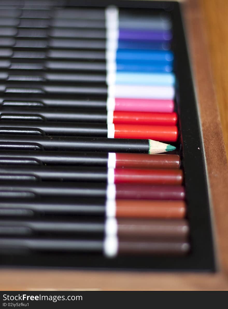 A line of drawing pencils with the green one turned around lead-first. A line of drawing pencils with the green one turned around lead-first