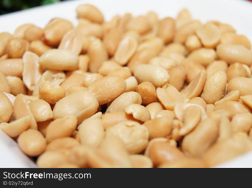 Roasted and salted peanuts on white bowl