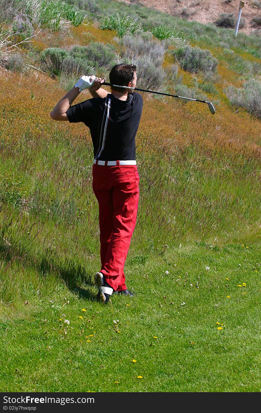 Young golfer playing a shot from the semi-rough