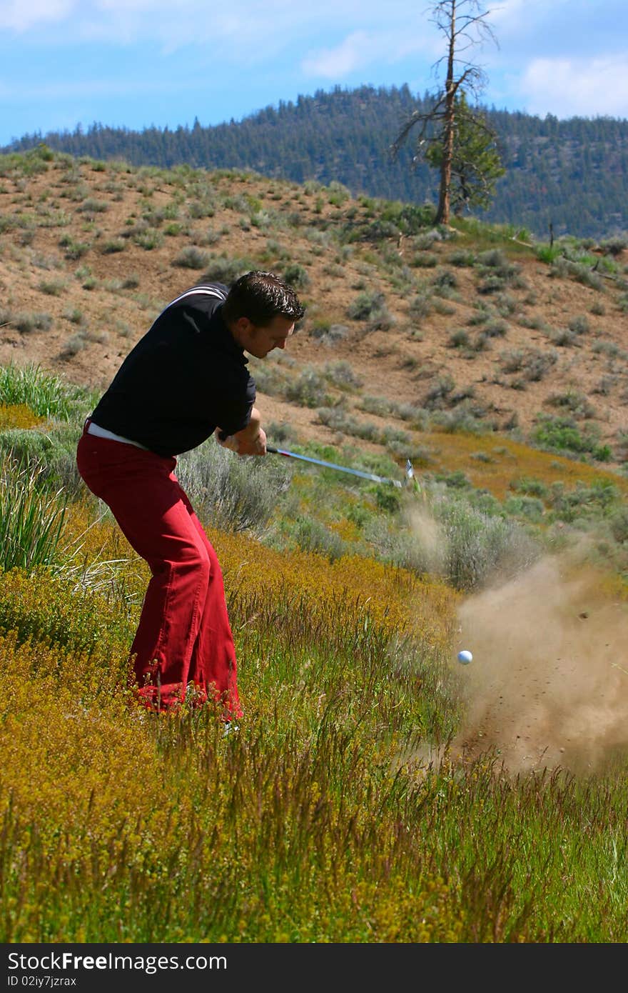 Young golfer playing a shot from the rough