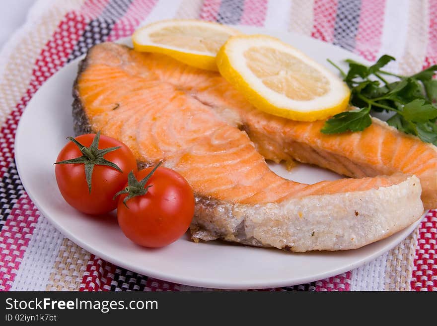 Grilled salmon with lemon on a white plate