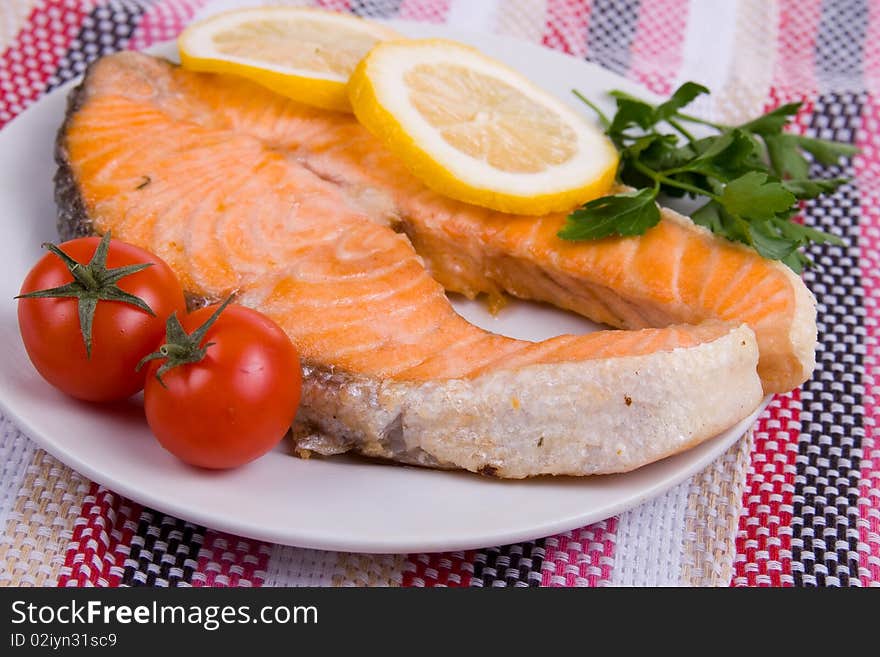 Grilled salmon with lemon on a white plate