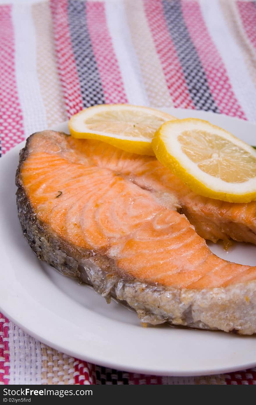 Grilled salmon with lemon on a white plate