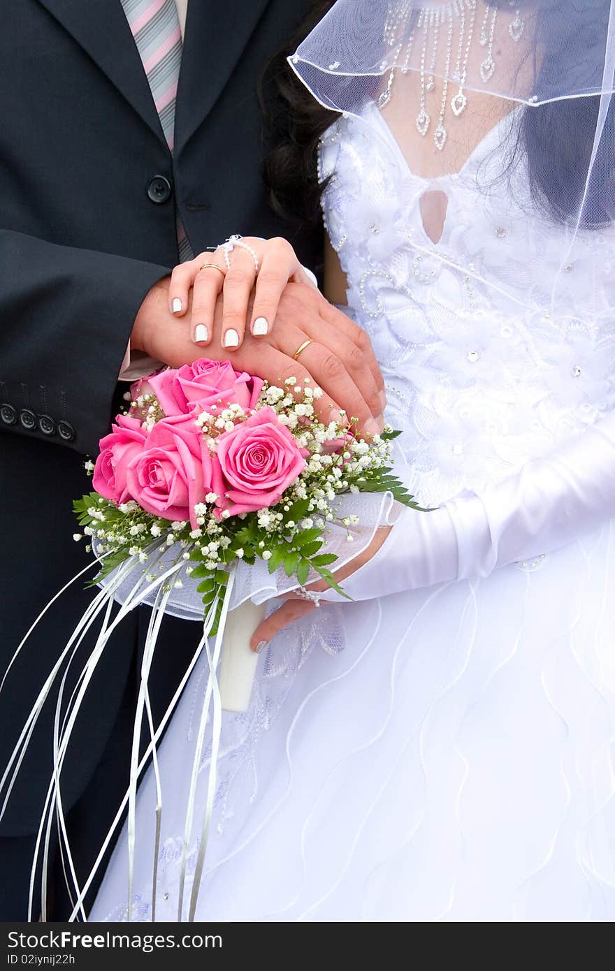 Hands newlyweds on the wedding bouquet