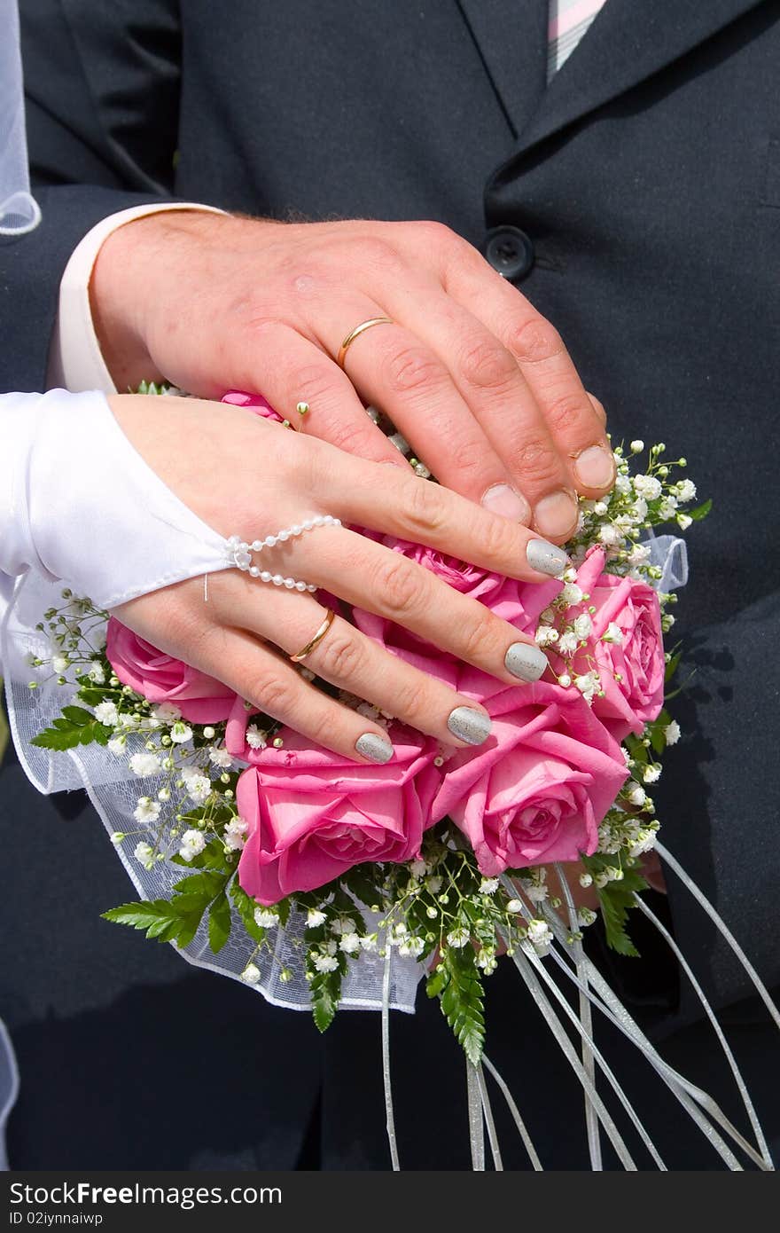 Hands newlyweds on the wedding bouquet