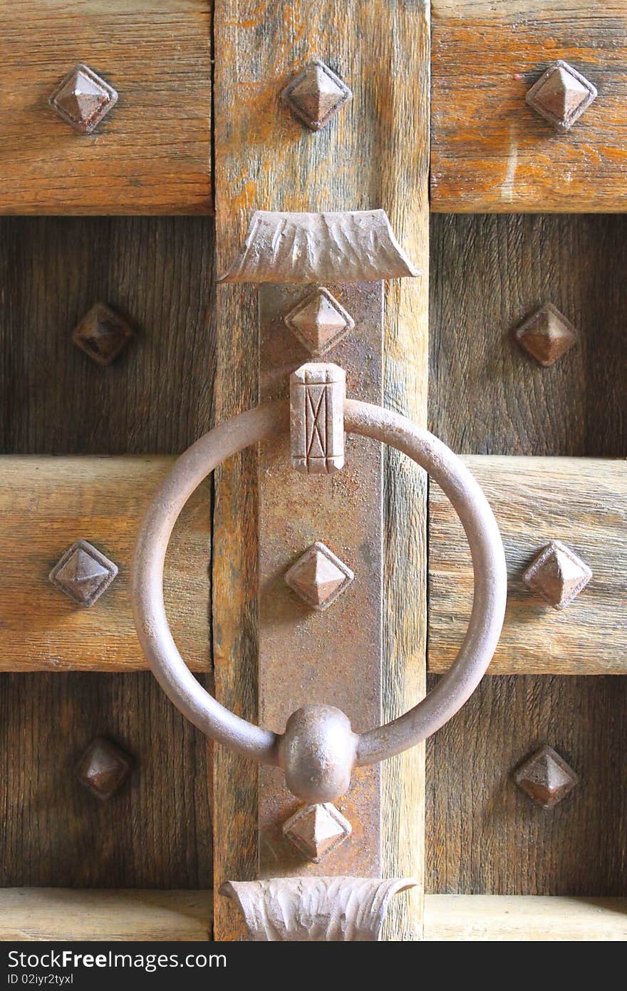 A Medieval Door Knocker comes in iron on a grand wooden door.