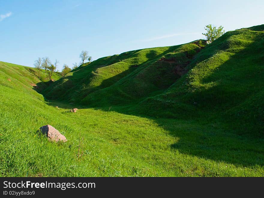 Shows the hills, grass, wood and sky.