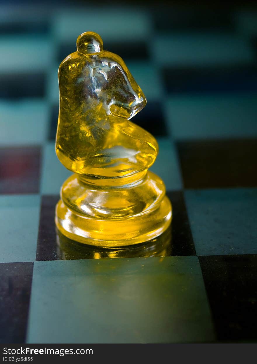 Knight a glass chess piece with glass Chess board in the background.The knight is the next piece on the board. In olden times, knights were wealthy individuals. On the chessboard, the knights are placed on either side of the bishops, showing their place in terms of wealth and importance. You can only move a knight in an L-shape.  The knight is the only piece on the board that may jump over other pieces. The knight moves two squares horizontally or vertically and then one more square at a right-angle. The knight&#x27;s move is shaped like an “L”. The knight always lands on a square opposite in colour from its initial square.