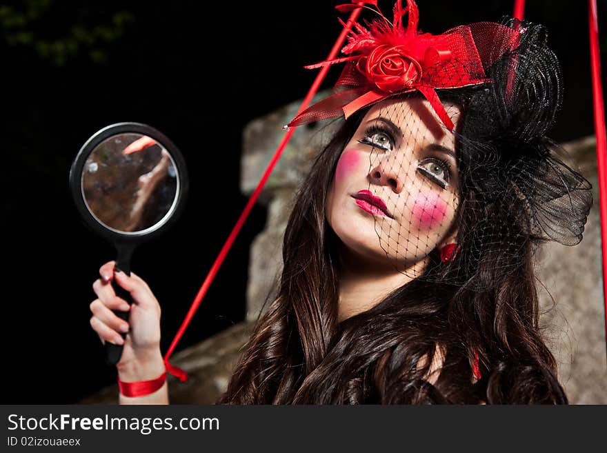 Beautiful girl wearing red hat and striped skirt posing as a marionette (puppet on a string)