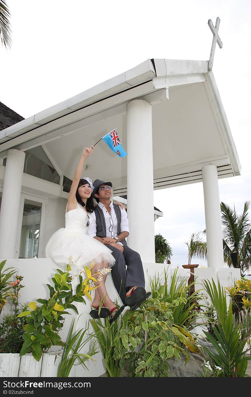 A happy couple posting in front of a chapel, they are going to get married.